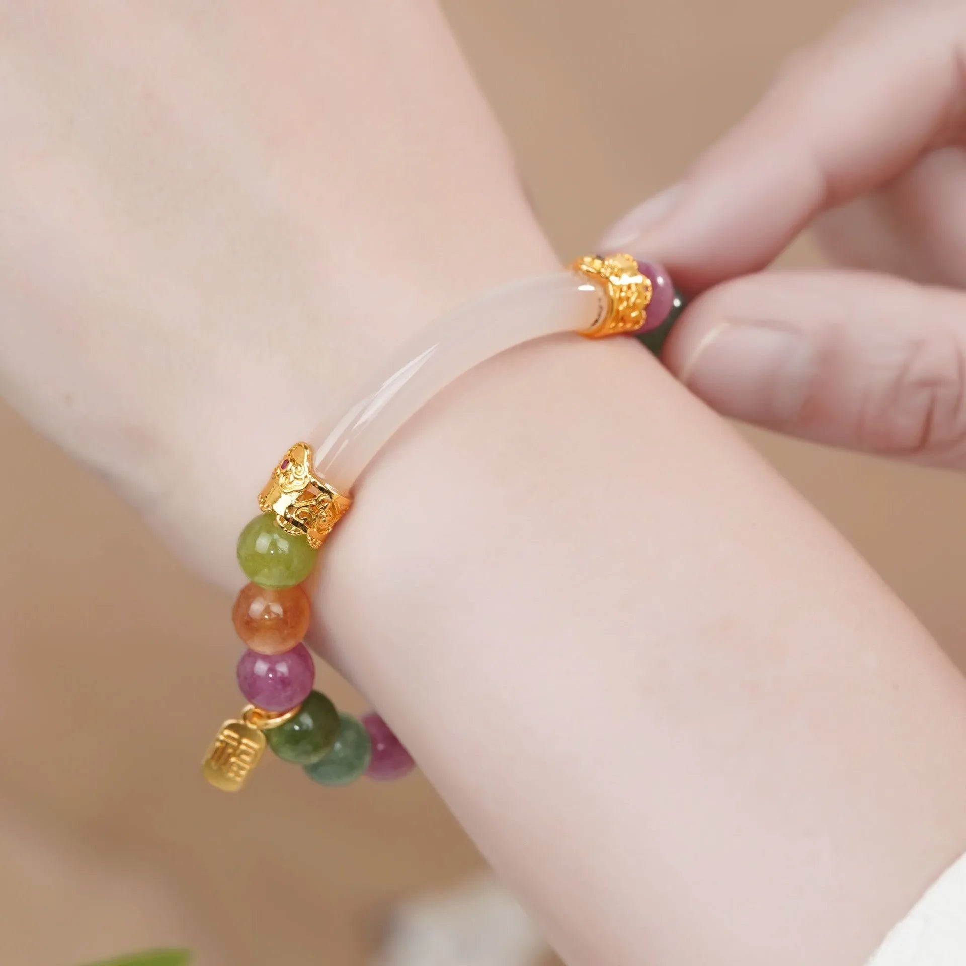 Rainbow coloured tourmaline half bracelet for women on a wrist, showing electroplated finish.
