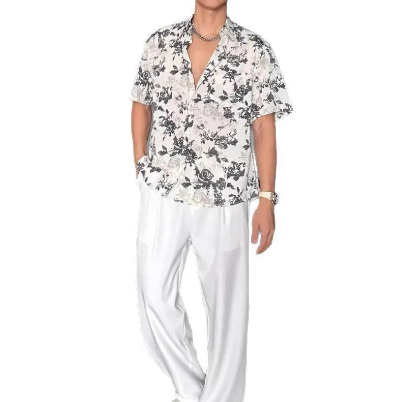 Man's loose fit black short sleeve shirt with floral pattern, worn open in cardigan style.