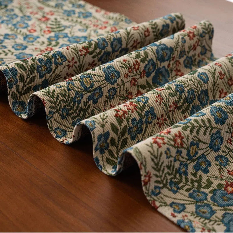 Dark blue and white striped jacquard table runner with tassel trim laid on a wooden dining table.