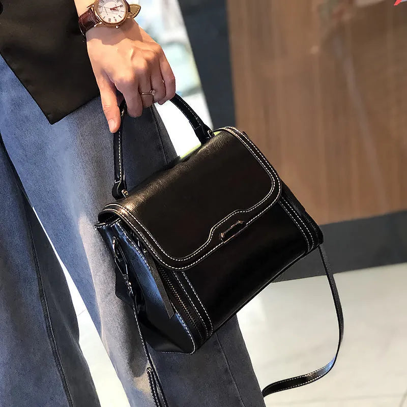 Women's brown genuine oil wax leather messenger bag showing front view with double straps and visible sewing details.