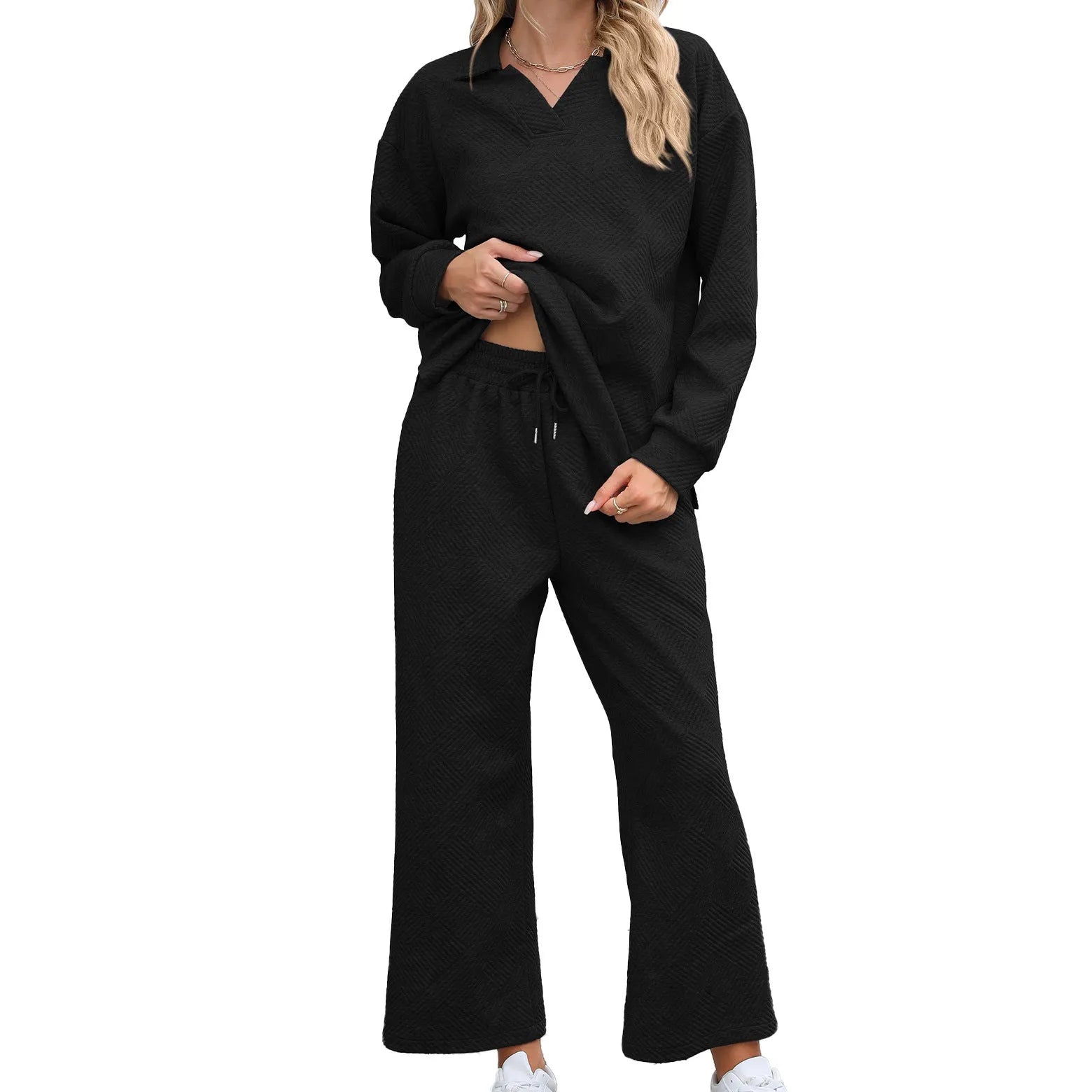 Woman wearing a knitted jacquard long sleeve sweater and matching elastic waist cropped trousers in a solid colour.