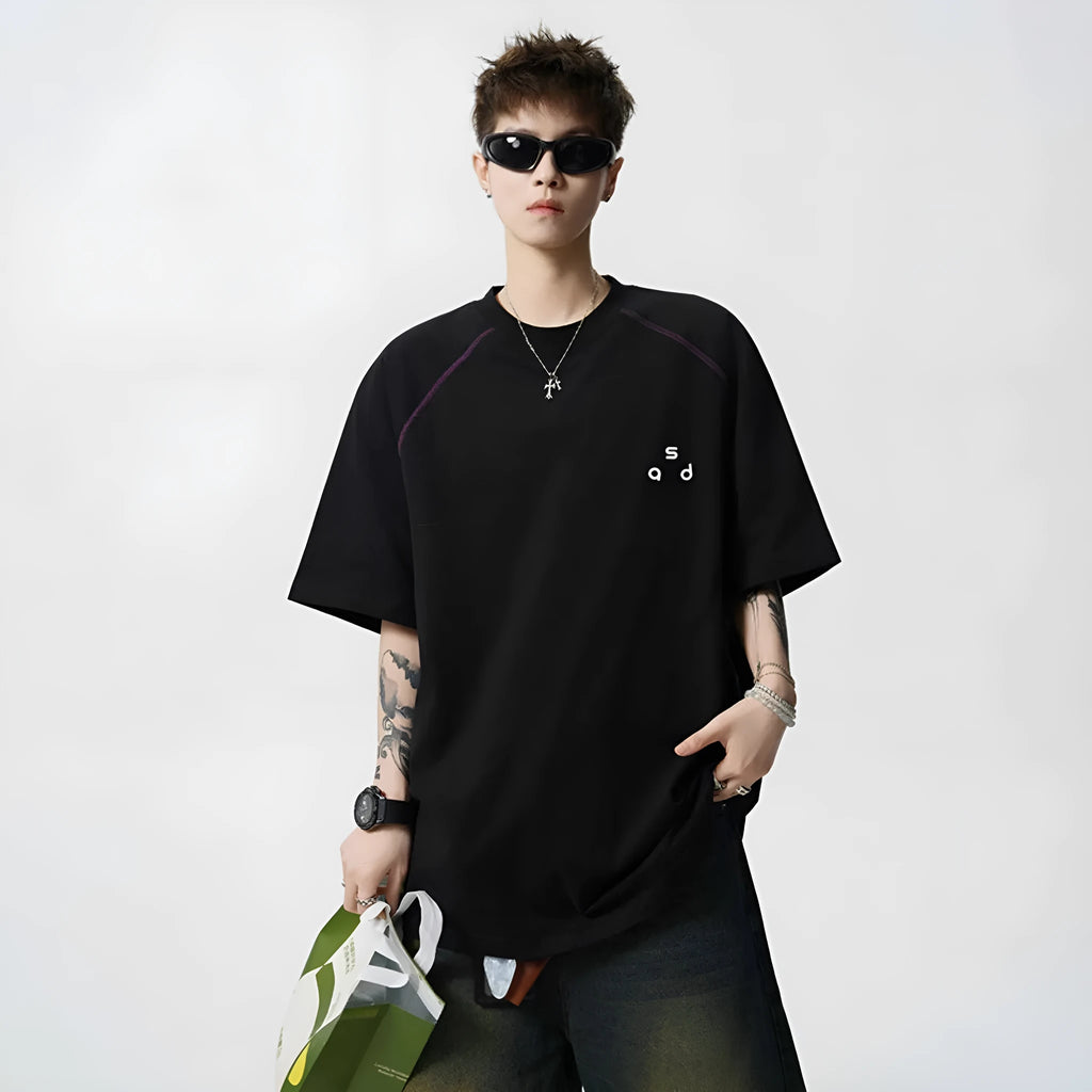 Man wearing a loose-fit black cotton t-shirt with a white letter print on the chest.
