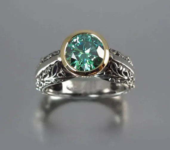 Gold-plated flower-shaped ring with a green gemstone on a silver-tone band, shown from above.