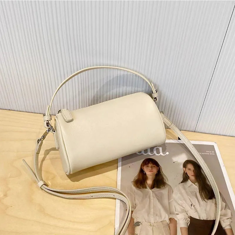 A soft genuine leather cylindrical crossbody bag for mobile phones in street style.