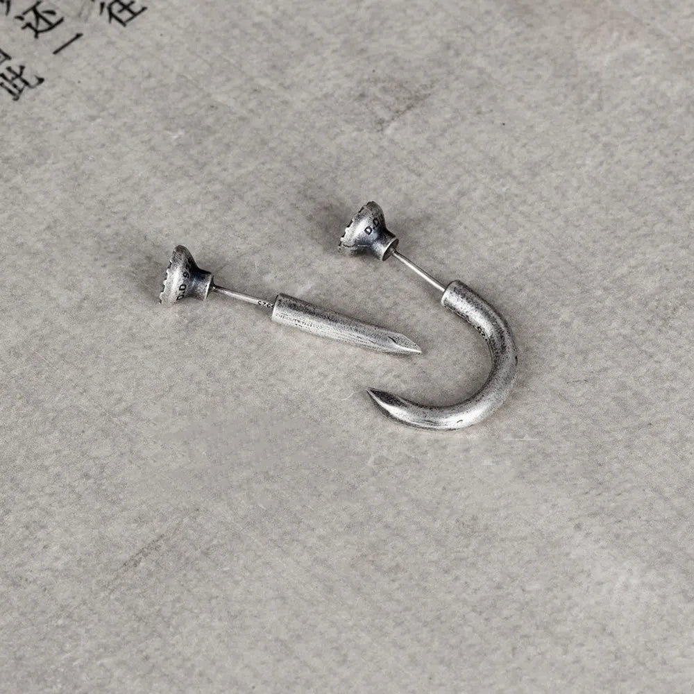 Close-up of a sterling silver S925 punk-style earring shaped like a retro nail, shown on a hook back.