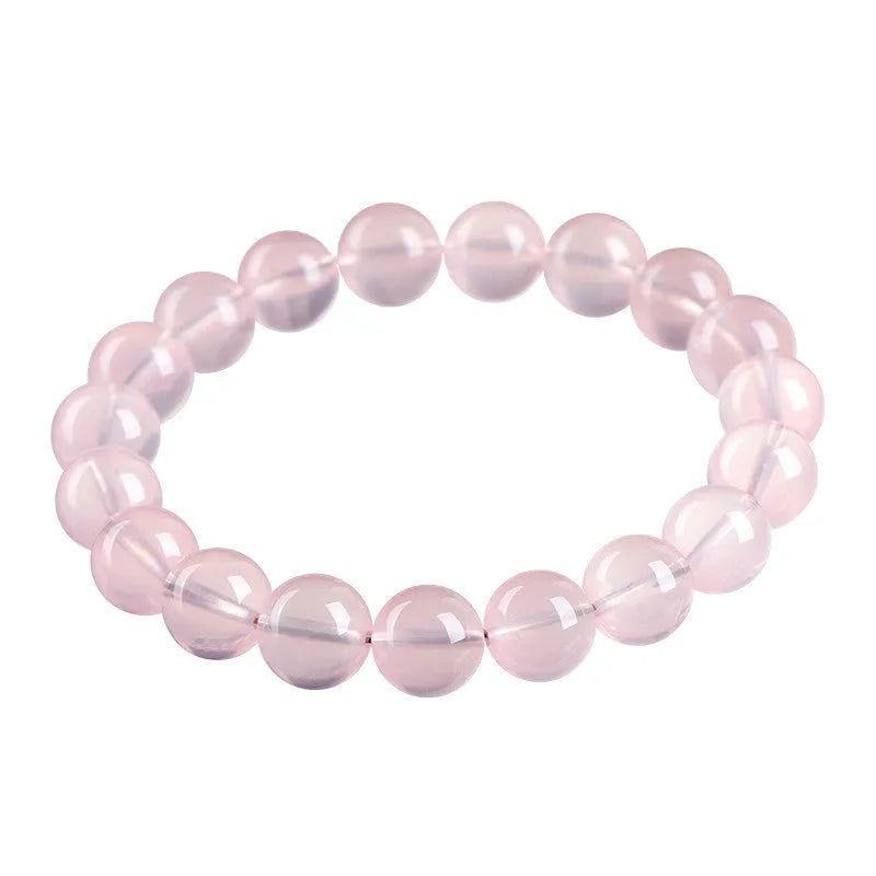 Close-up of a polished natural starlight crystal round bead bracelet in pink, showing single circle design.