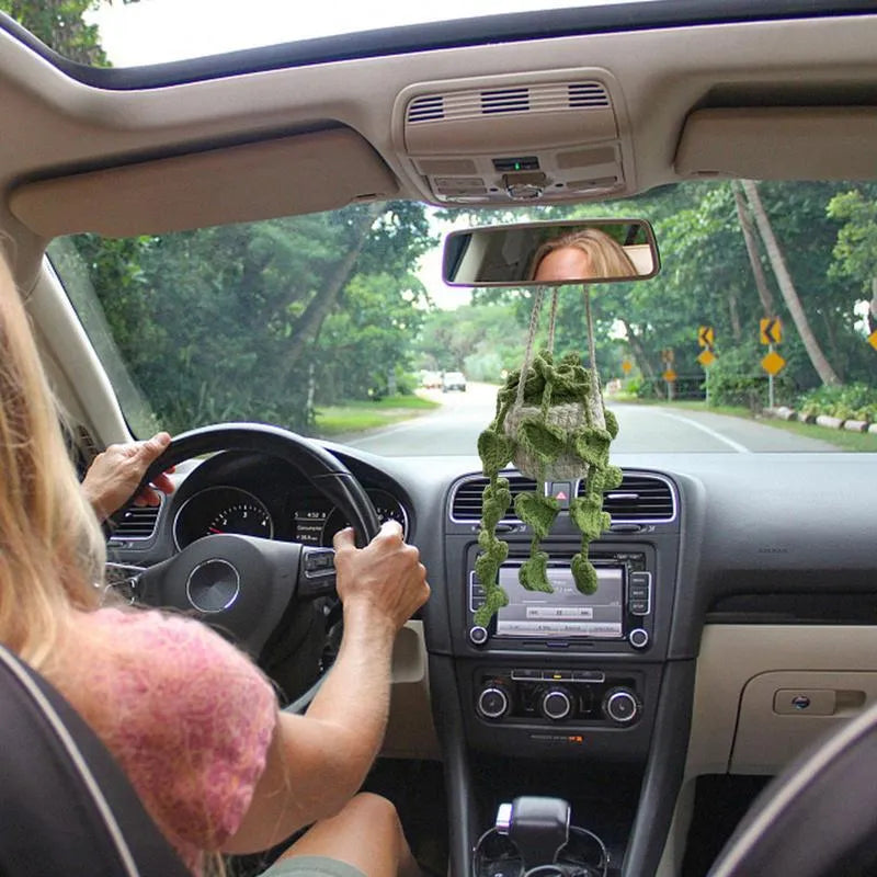 Green and white crochet wool car plant decoration with hanging rope on car dashboard