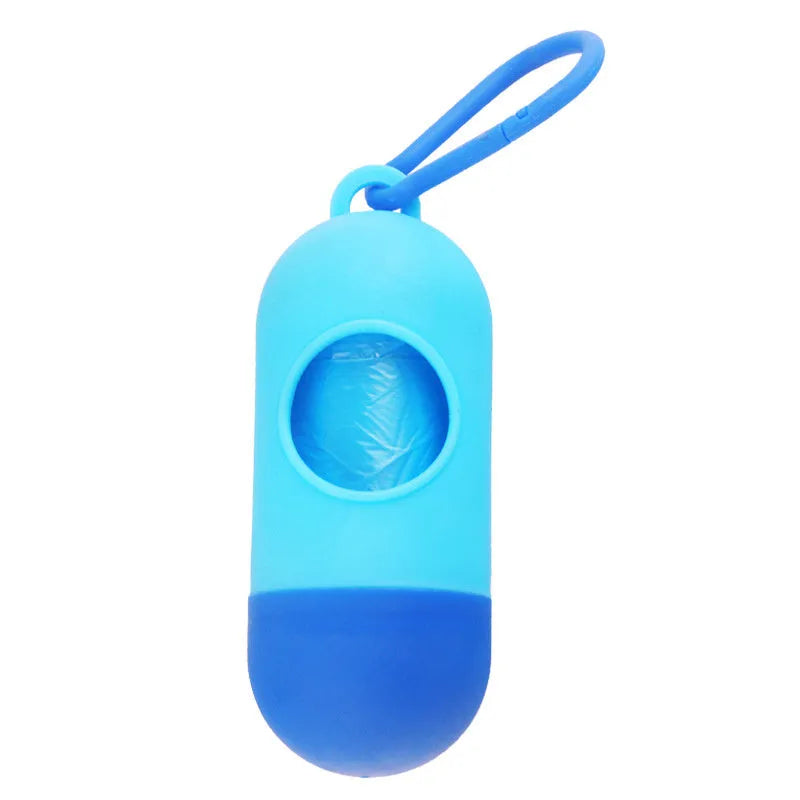 Compact black dog poop bag holder with hook and Velcro strap, shown attached to a pair of trousers.