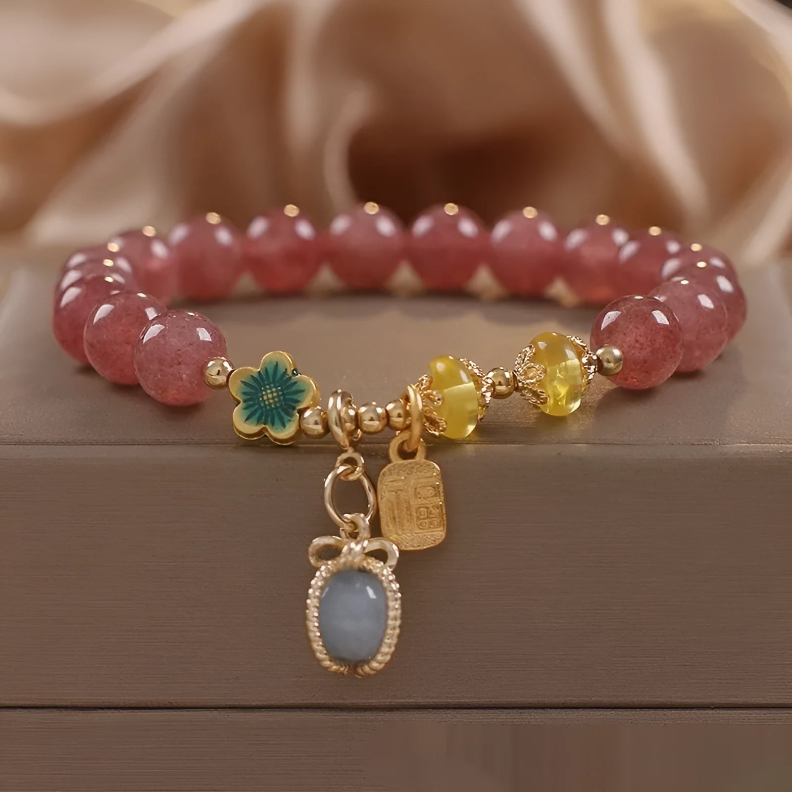 Red women's beaded bracelet made with natural strawberry quartz stones, alloy spacers, and rhinestone accents.