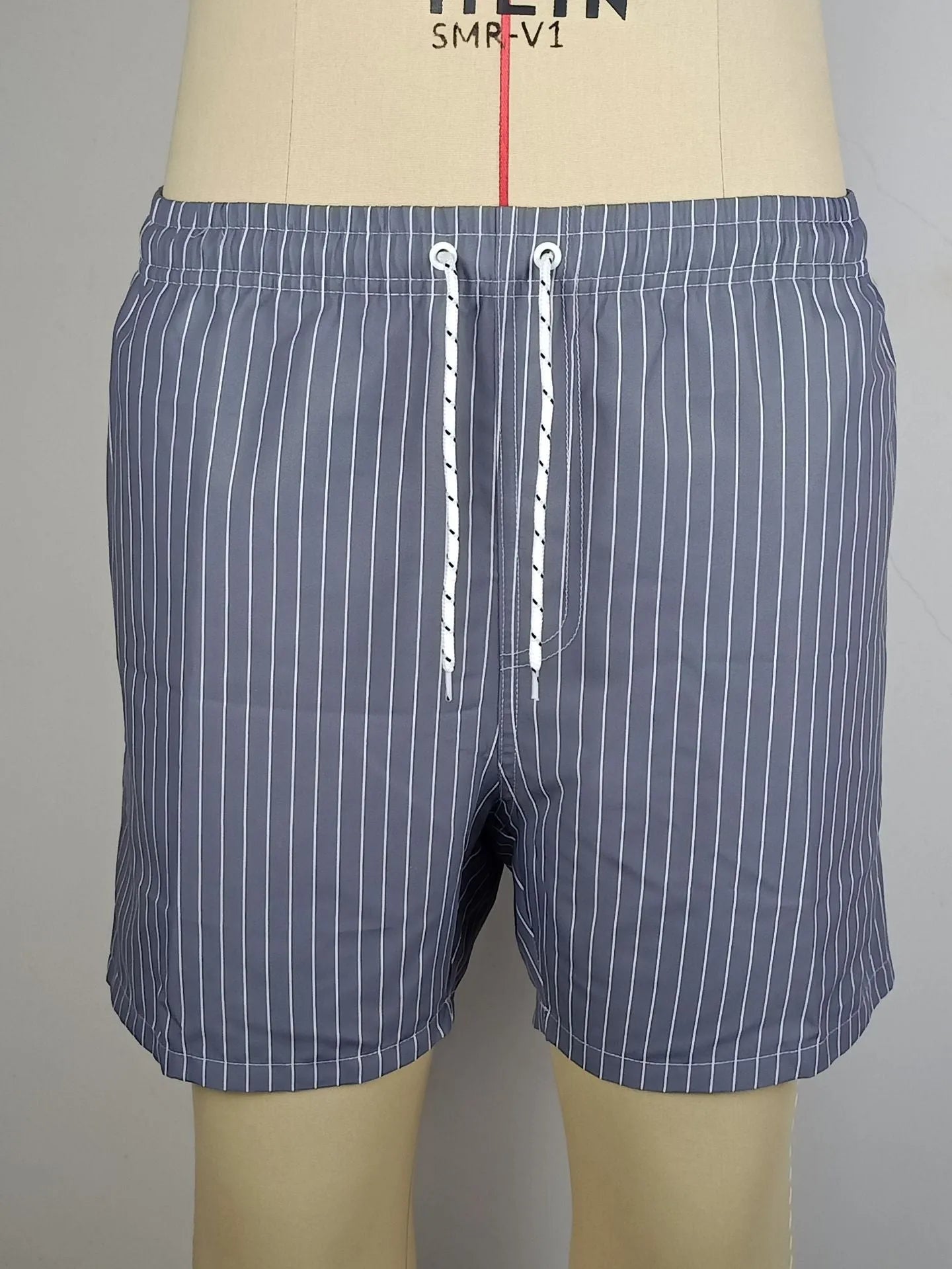 Polyester fibre beach shorts with digital printed striped triangle lining in straight leg style