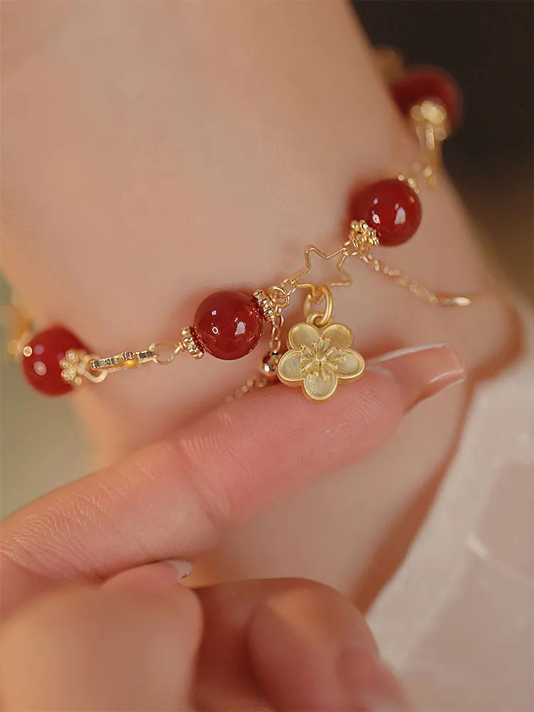 Red agate double layer women's bracelet with peach blossom design on adjustable string.