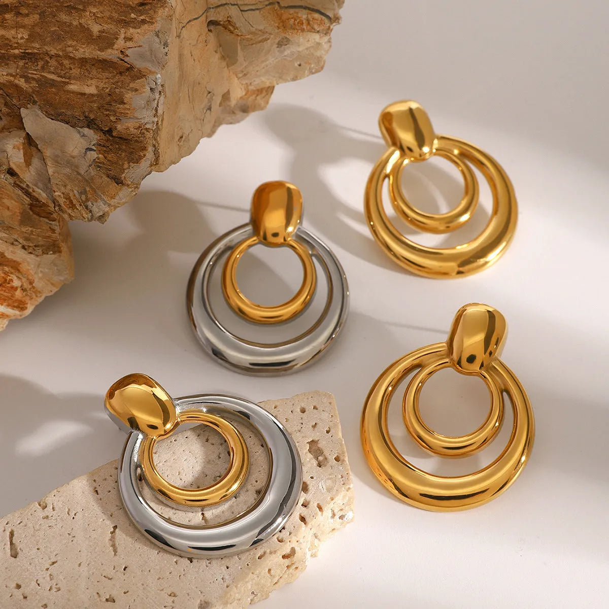 Golden round double layer hollow stud earrings with geometric design on white background
