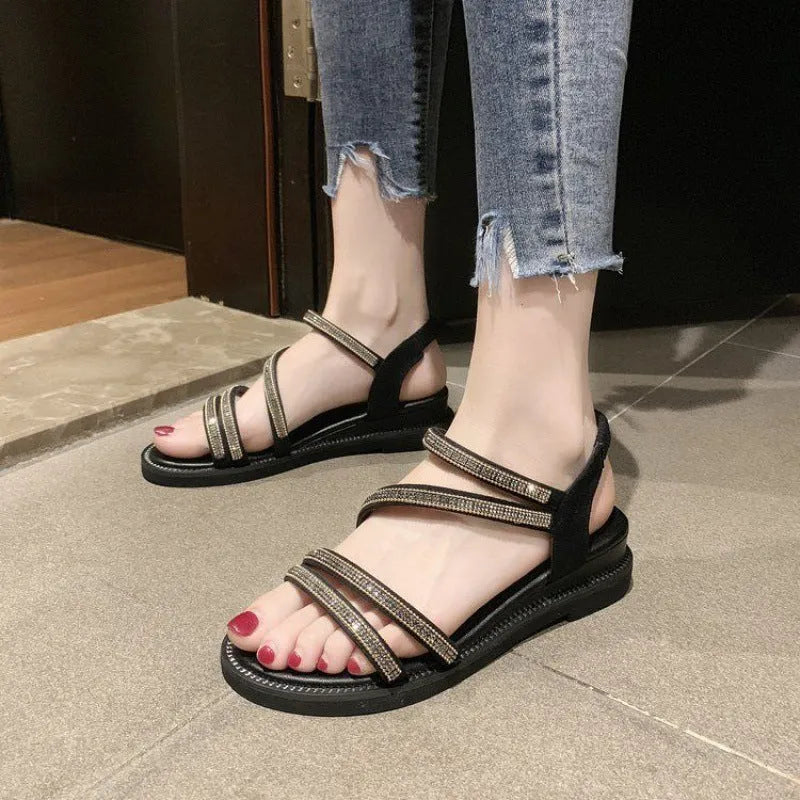 Women's silver flat sandals with rhinestone decoration and elastic band, shown on a white background.