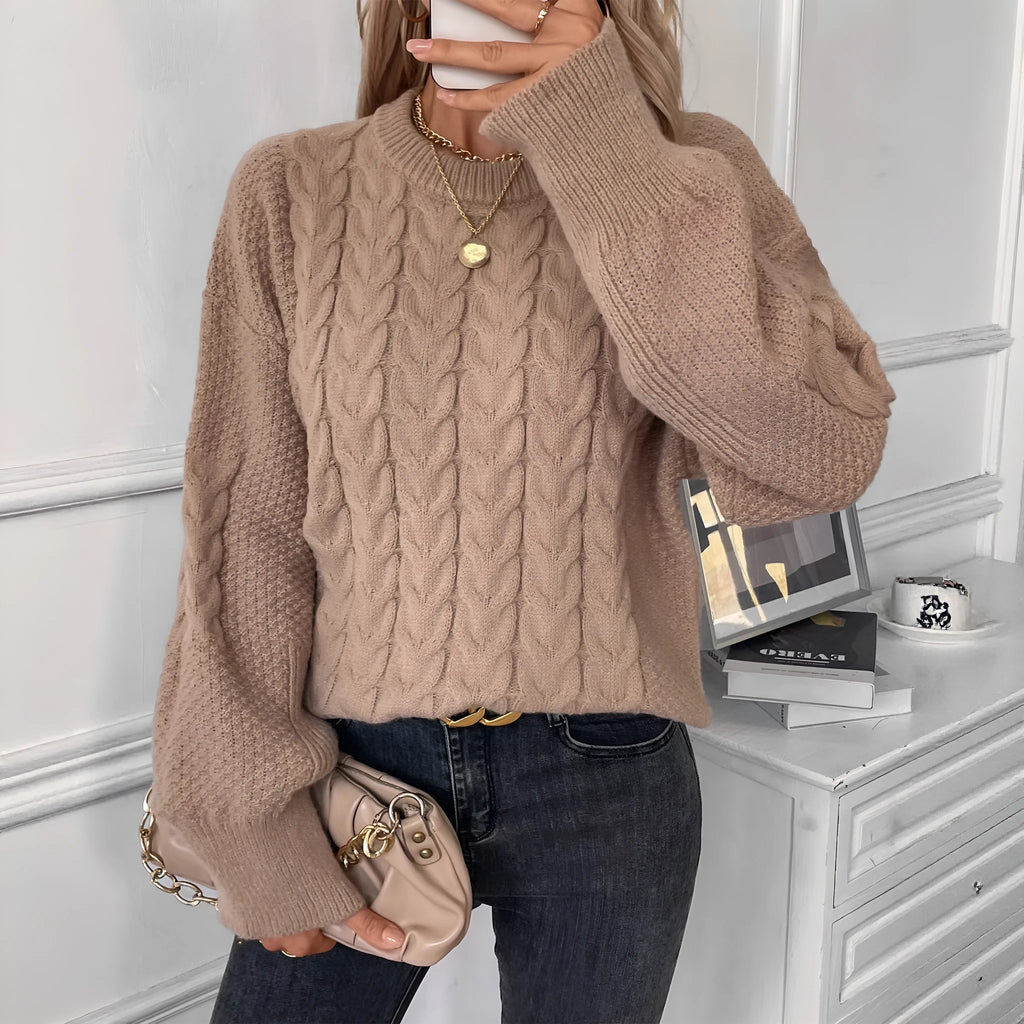 Woman wearing a loose beige casual sweater with a twisted texture detail on the front.