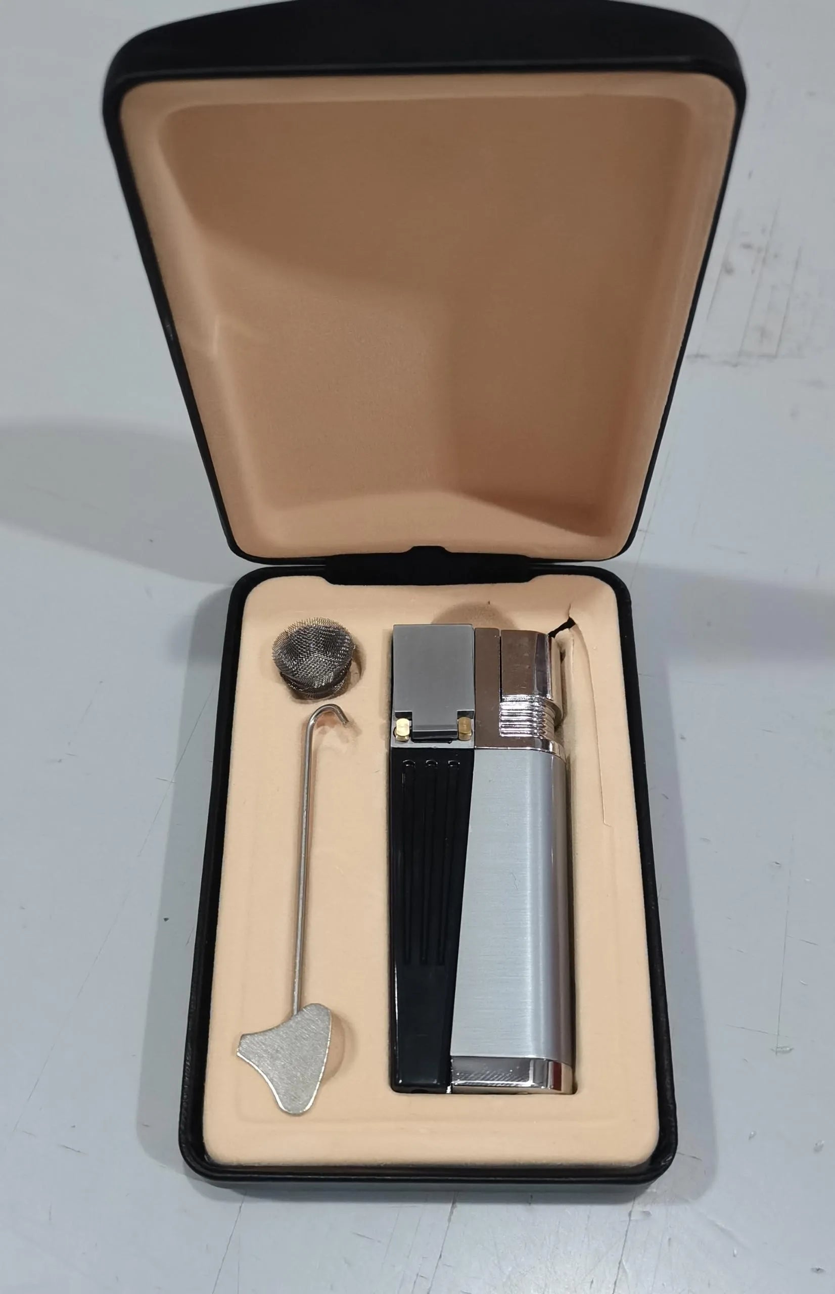Silver foldable metal pipe lighter shown open, revealing the lighter mechanism and a small stash compartment.