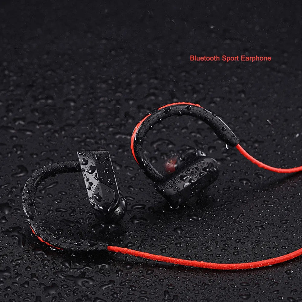 Black wireless Bluetooth neckband earphones with earpieces showing, placed next to a USB charging cable on a white background.