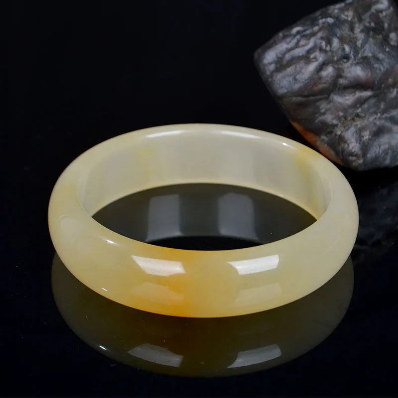 Natural light green jade bracelet in Chinese style, shown on a wrist, with a polished surface.