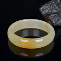 Natural light green jade bracelet in Chinese style, shown on a wrist, with a polished surface.