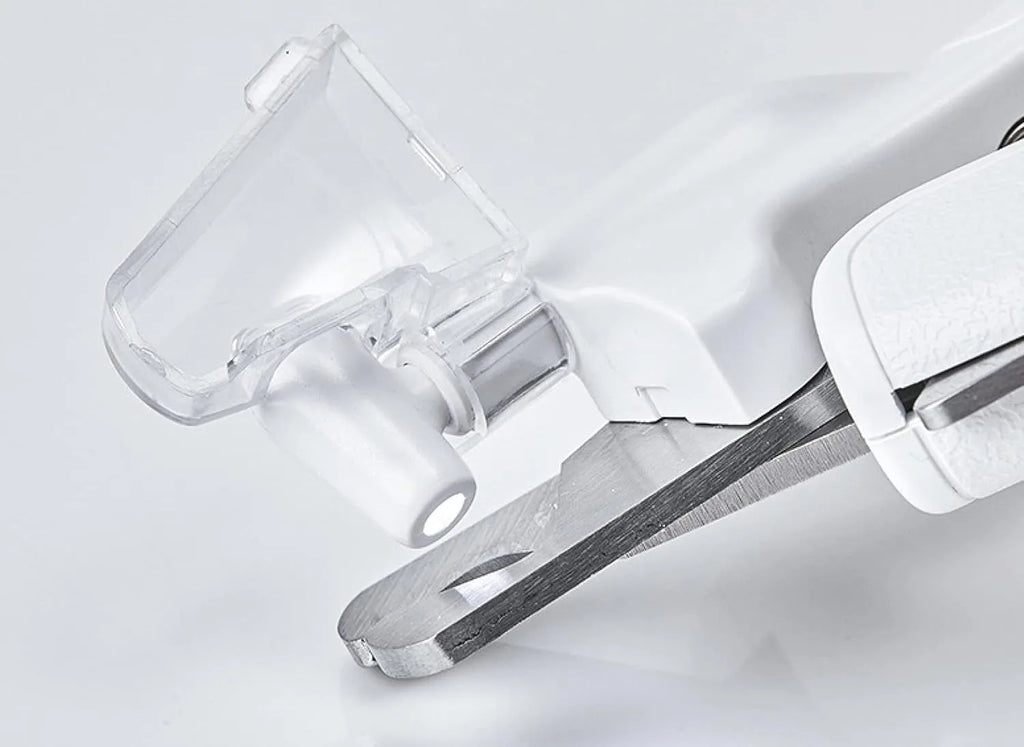 White pet nail clippers with LED light, anti-splash guard, and a nail file on a table.