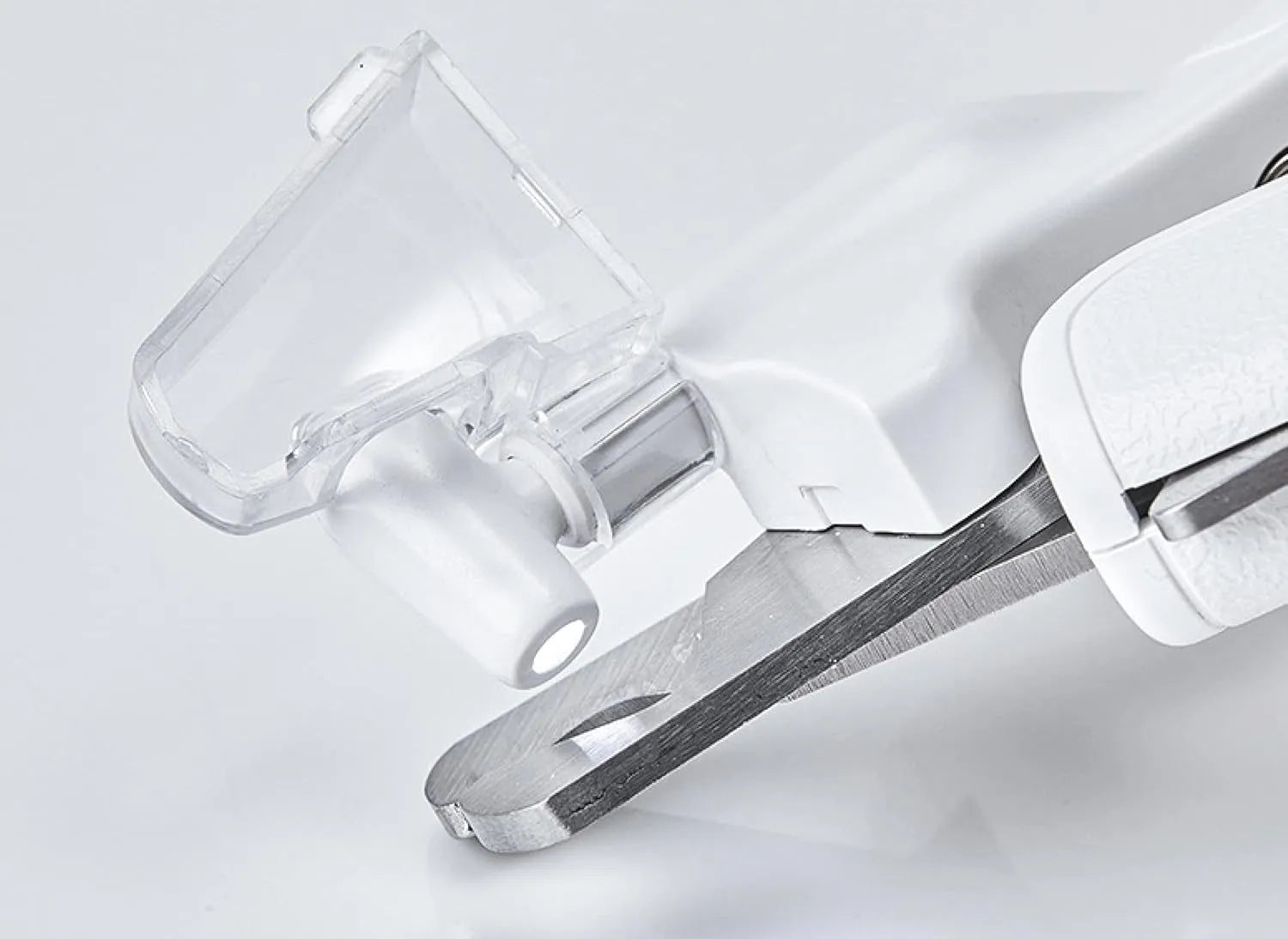 White pet nail clippers with LED light, anti-splash guard, and a nail file on a table.