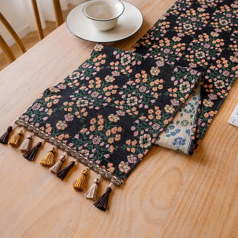 Dark blue and white striped jacquard table runner with tassel trim laid on a wooden dining table.