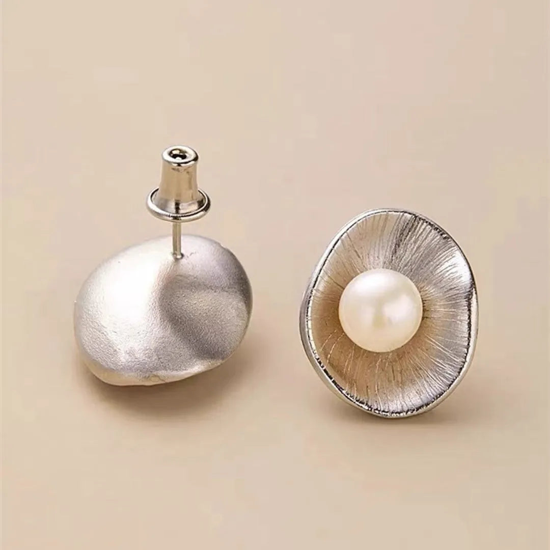 A pair of gold geometric sterling silver ear studs with small white pearl details on a post back.