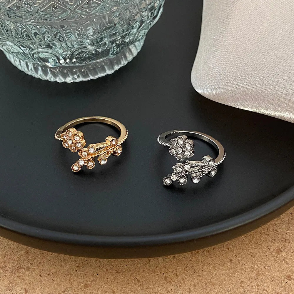 Gold and white women's open ring with floral leaf design and diamond treatment.