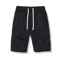 Man wearing loose-fit black cropped trousers with multiple pockets, summer casual style