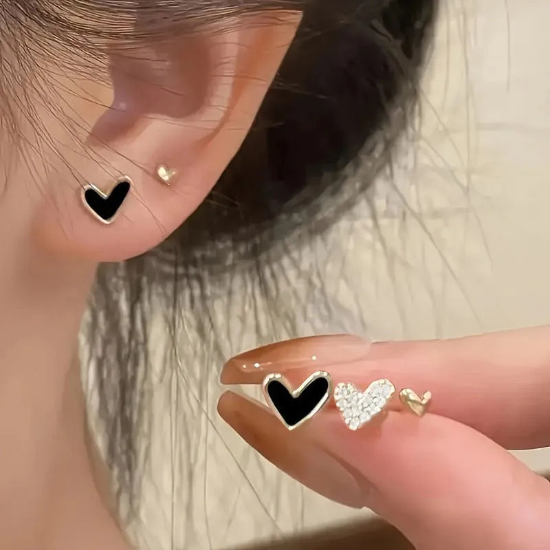 Set of three pairs of women's heart-shaped alloy drop earrings in gold, black, pink colours.