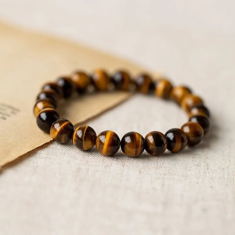 Single circle tigereye stone Buddhist prayer beads bracelet on wrist, showing ethnic design.