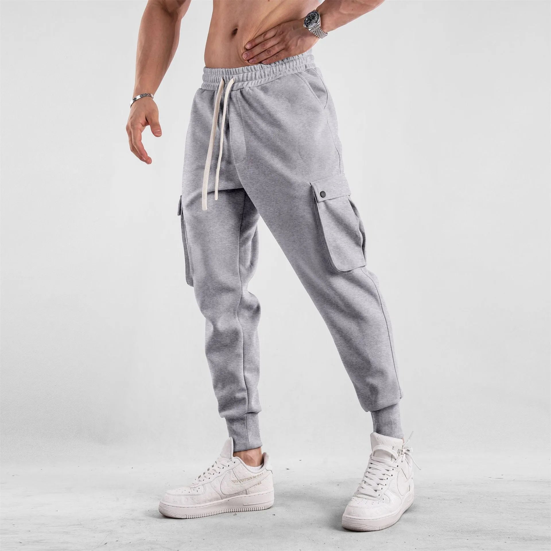 Men's loose fit cotton trousers with ankle-tied cuffs and multiple pockets in a light grey colour.