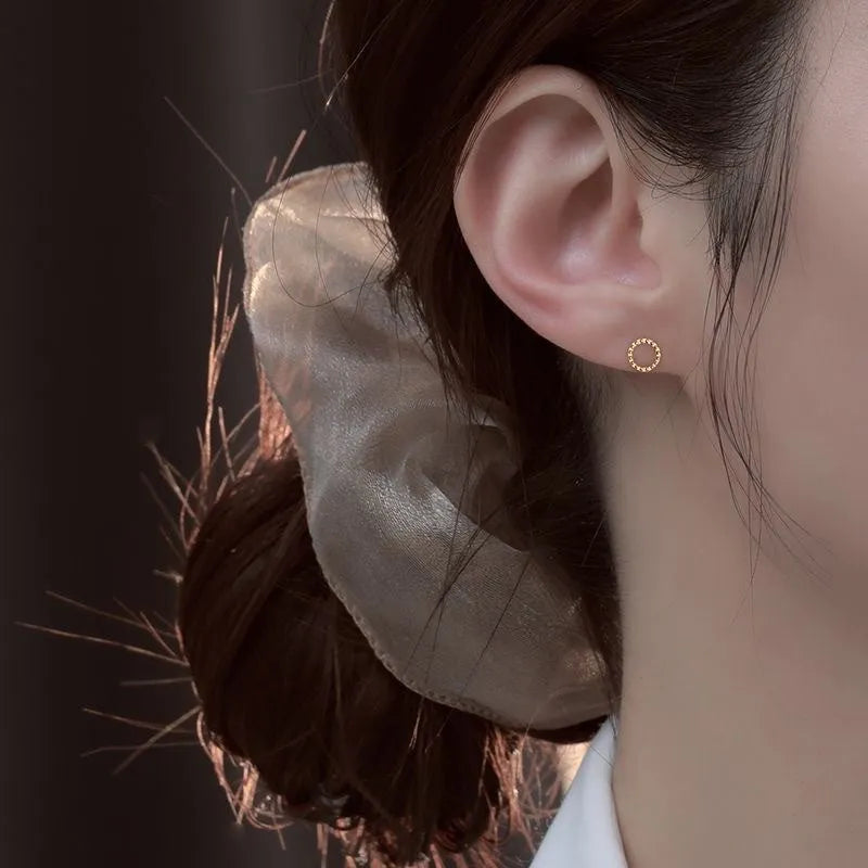 Small spiral geometric ear studs in gold hollow thread design with mixed material build and electroplated finish