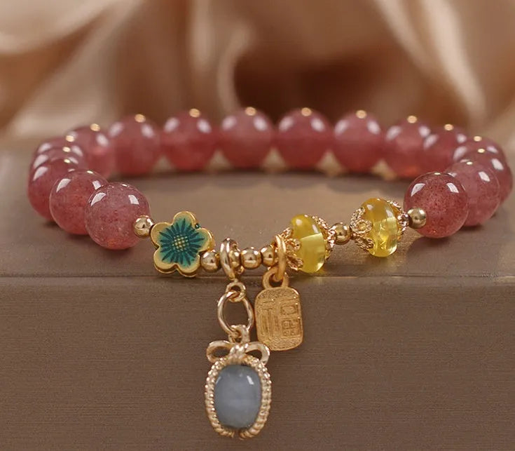 Red women's beaded bracelet made with natural strawberry quartz stones, alloy spacers, and rhinestone accents.