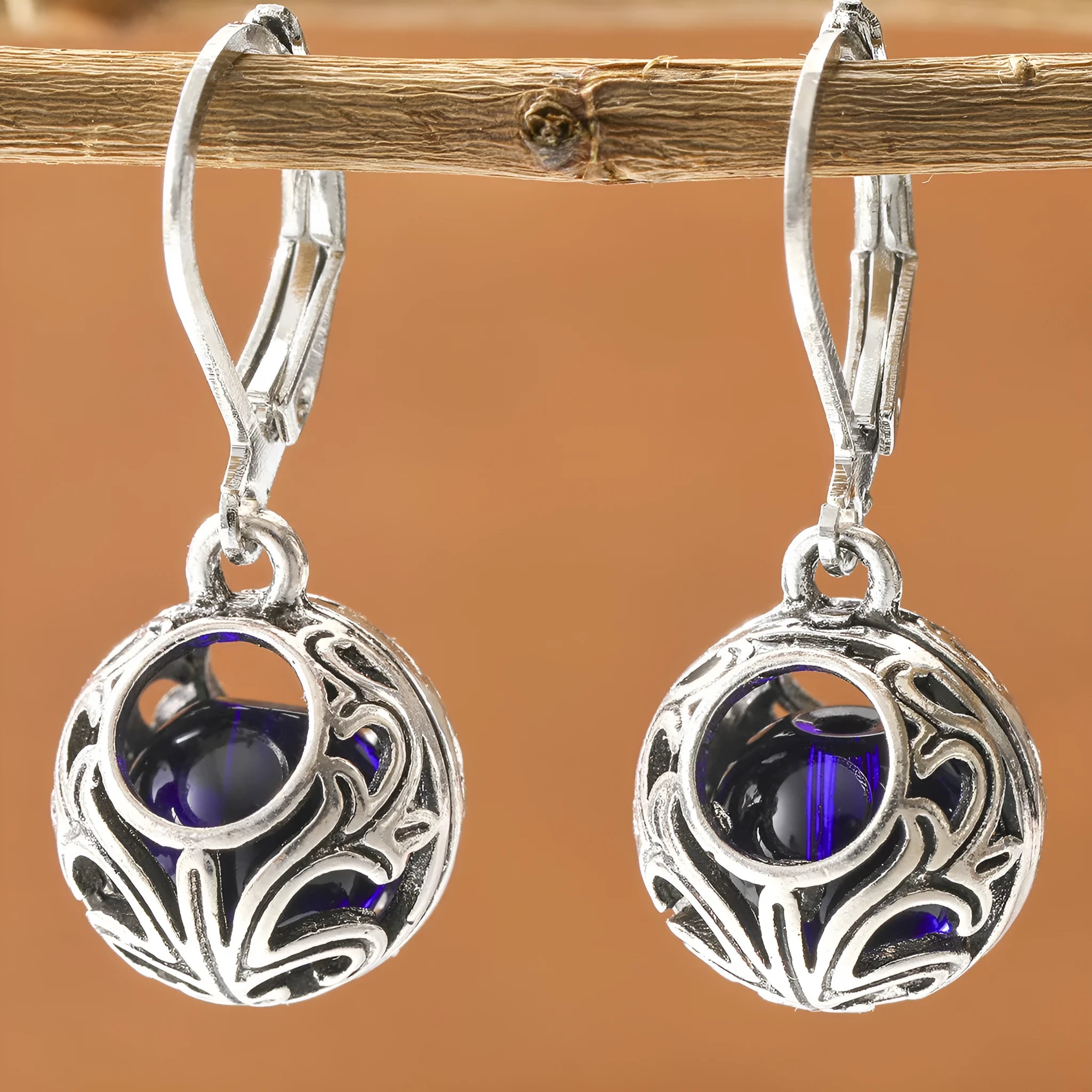 Silver tone pendant earrings with hollow geometric design, blue gemstones, and vintage engraving detail