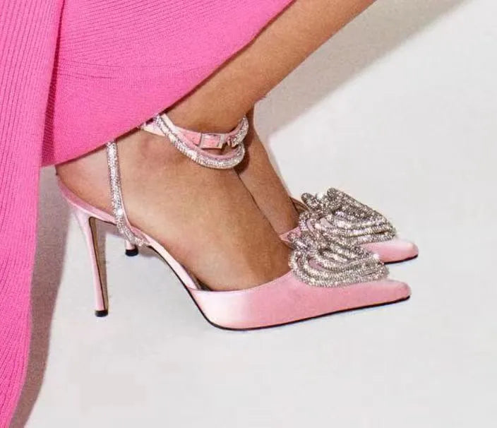 Women's pink satin sandal with rhinestone heart decoration, pointed toe, and cross-belt strap.