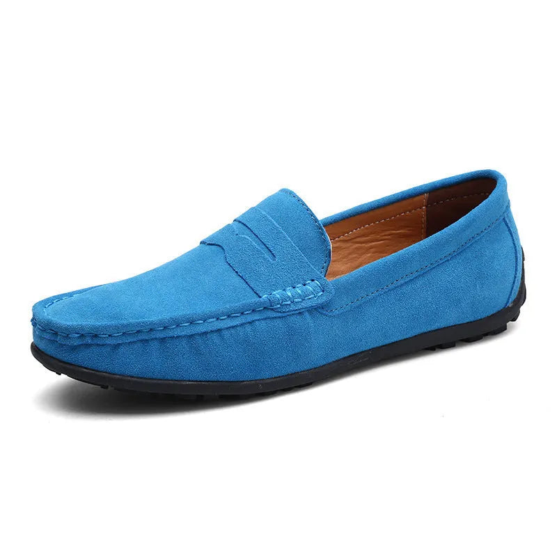 Men's suede slip-on loafers in black on a flat rubber sole, showing round toe and sewing detail.