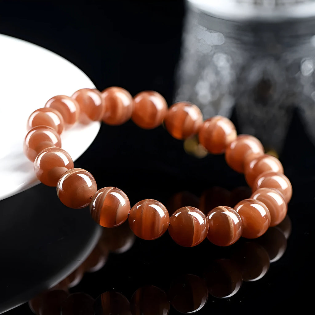 Natural rhodochrosite round bead bracelet with ruyi design on wrist.