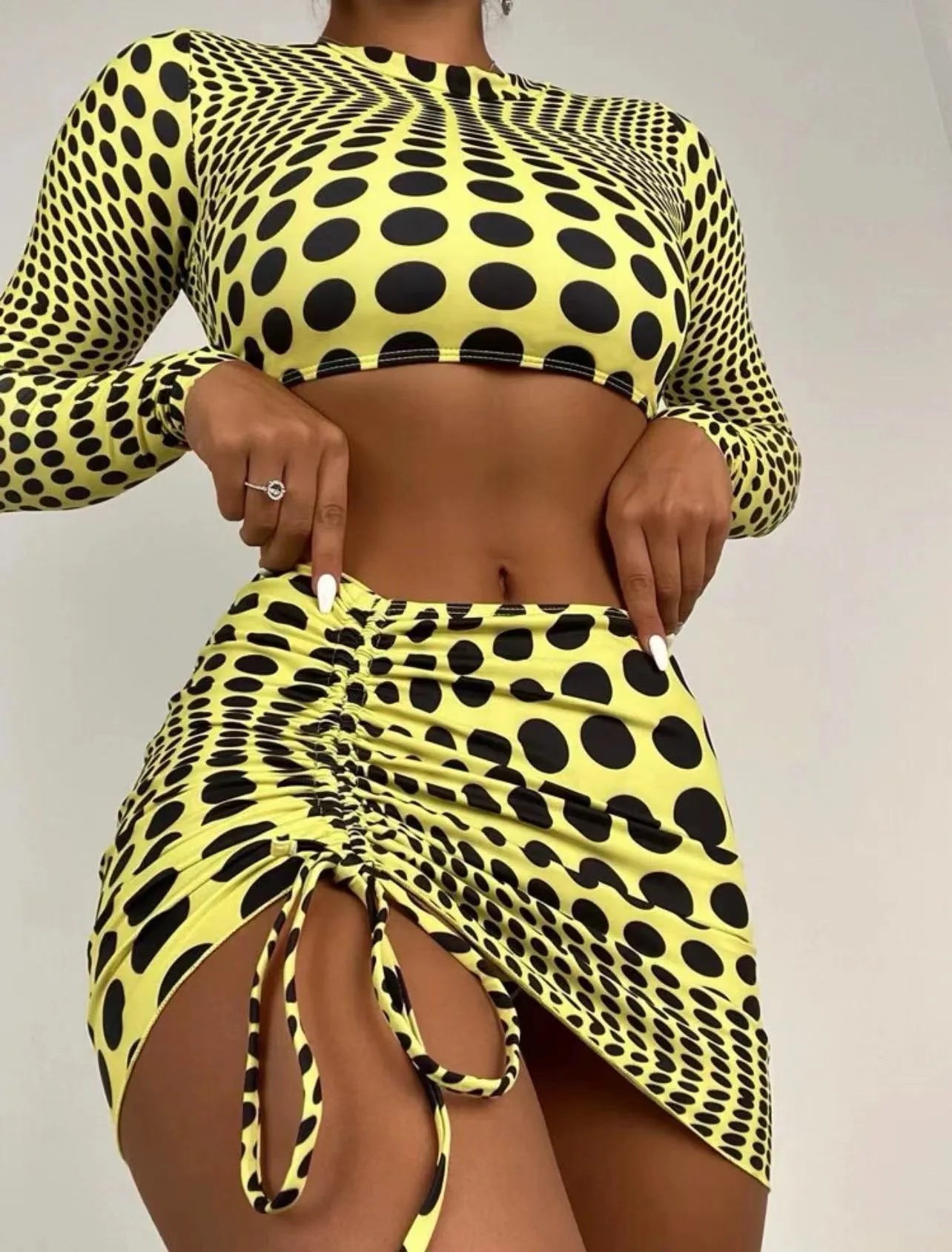 Women's green polka dot three-piece swimsuit set showing bra top and matching skirt