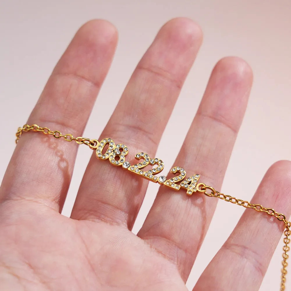 Stainless steel digital bracelet with crystal-set numbers on dial, shown in gold colour.