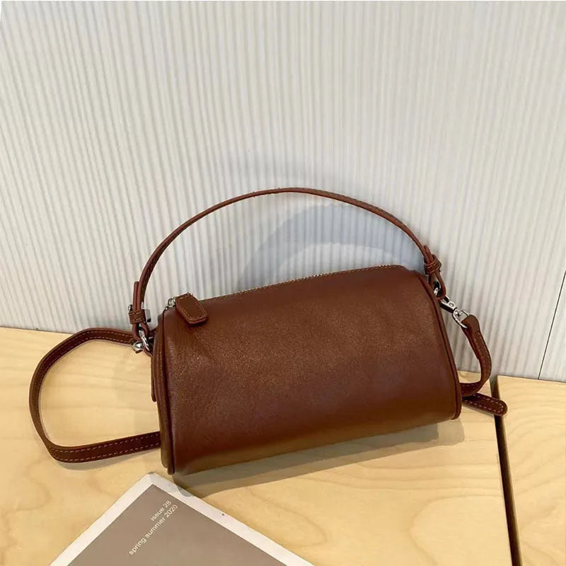 A soft genuine leather cylindrical crossbody bag for mobile phones in street style.