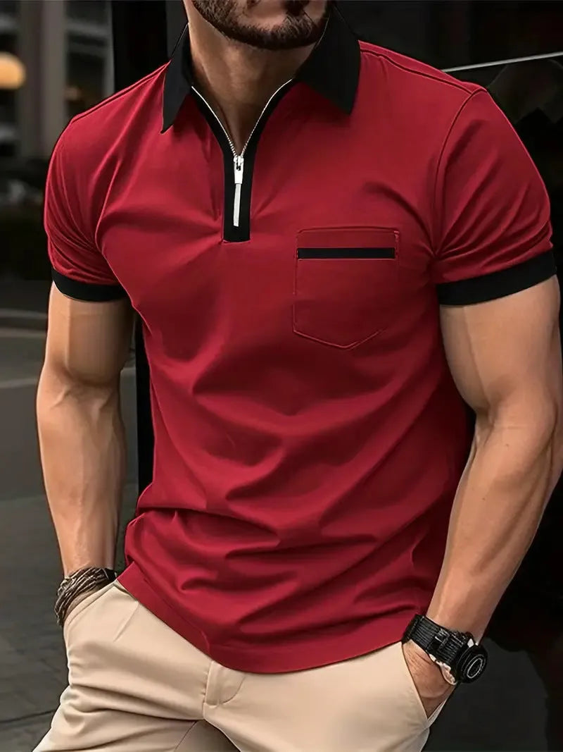 Man wearing a grey and navy blue casual t-shirt with a chest pocket and silver zip decoration detail.