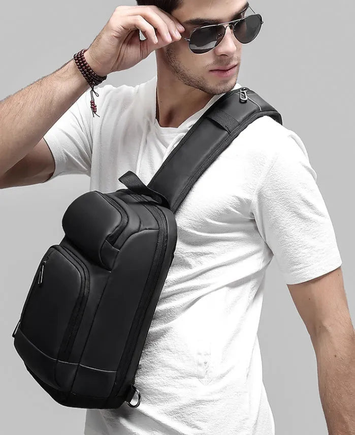 Black PVC outdoor shoulder bag showing computer pocket, air cushion strap, and organisational compartments
