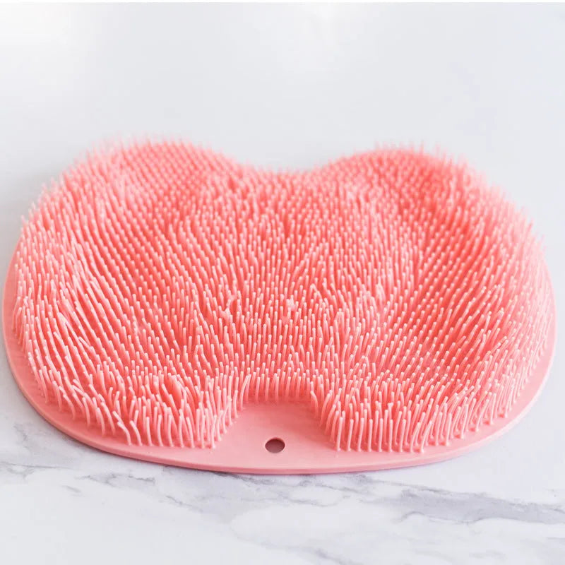 Orange silicone bristle bath brush with suction cup base on a bathroom floor.