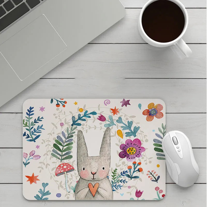Custom cartoon design on a small black thickened mouse pad with stitching, shown on a desk.