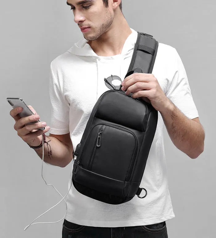 Black PVC outdoor shoulder bag showing computer pocket, air cushion strap, and organisational compartments