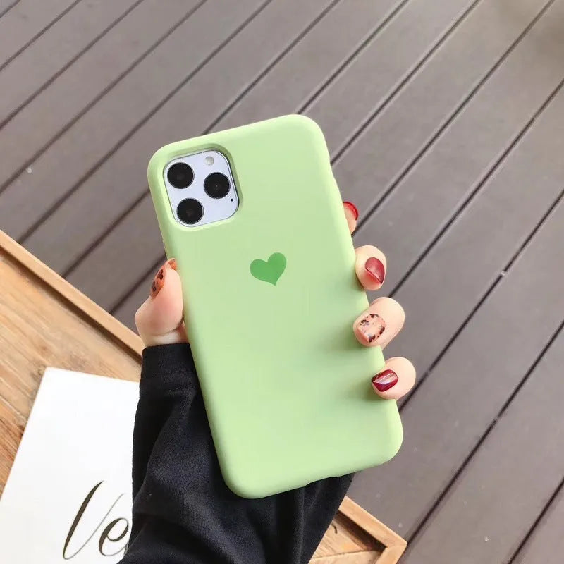 Solid colour silicone phone case for iPhone, shown in dark green, on a wooden surface.