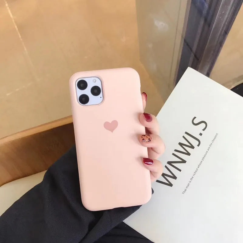 Solid colour silicone phone case for iPhone, shown in dark green, on a wooden surface.