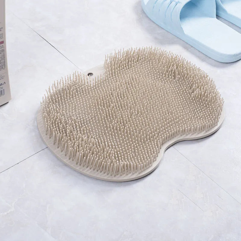 Orange silicone bristle bath brush with suction cup base on a bathroom floor.