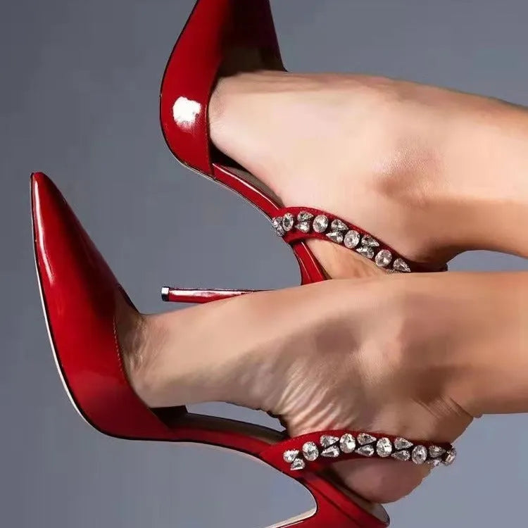 Pointed toe high heel sandals with rhinestone detail on the side, shown in patent leather.