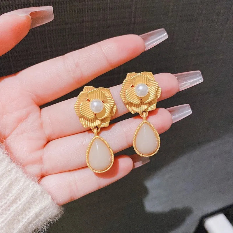 Gold flower stud earrings with a pearl, opal, and needle rose design on a white background.
